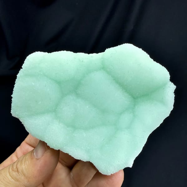 Pastel-green botryoidal aragonite plate from Yunnan, China, held in hand