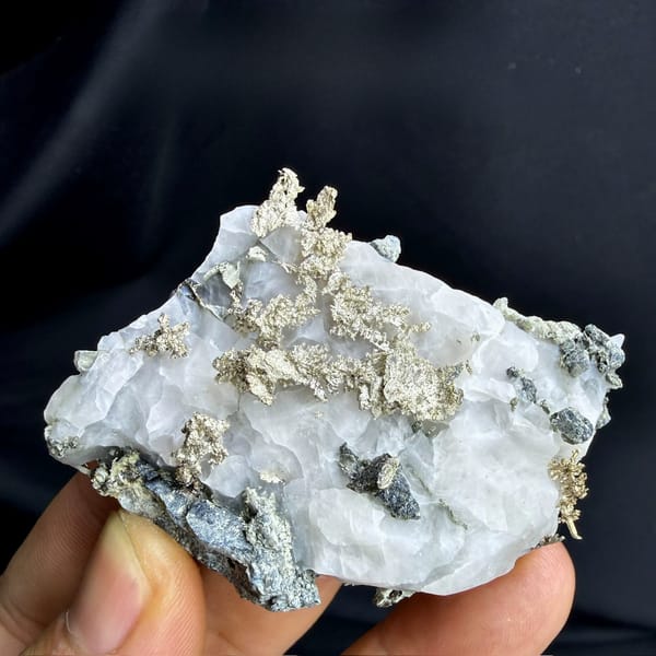 Native silver wires on white calcite from the USA, held in hand