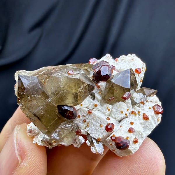 Smoky quartz with red garnets and hyalite opal on feldspar from Yunxiao, Fujian, China, close-up of the crystal faces
