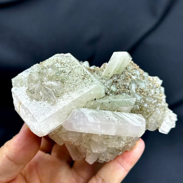 Large pink and green two-tone apophyllite crystals from Fujian, China, held in hand