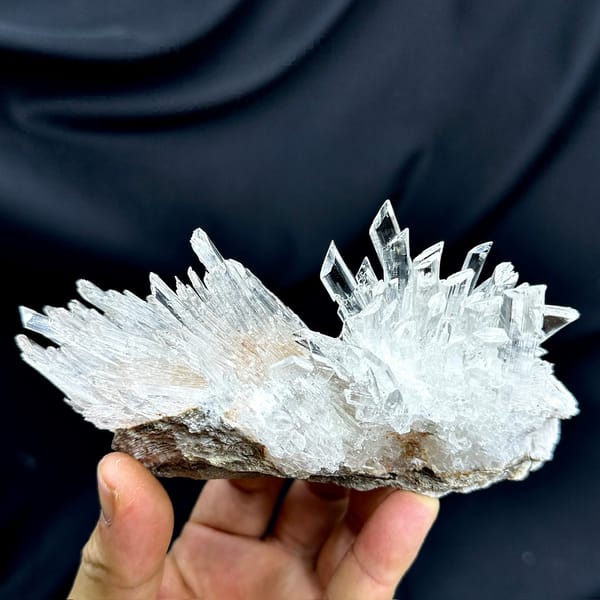Long fan of transparent gypsum prisms from Guizhou, China, held in hand