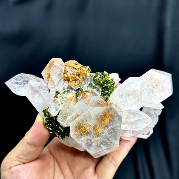 Large clear garden quartz crystals with green epidote from Sichuan, China, held in hand
