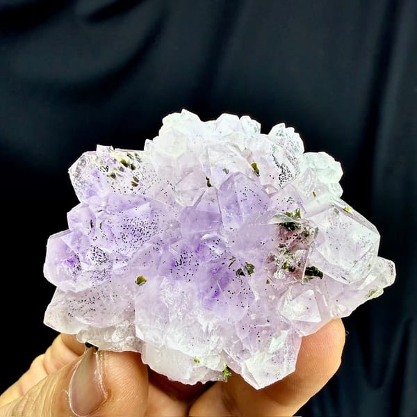 Rosette of pale purple-red garden quartz crystals from Sichuan, China, held in hand