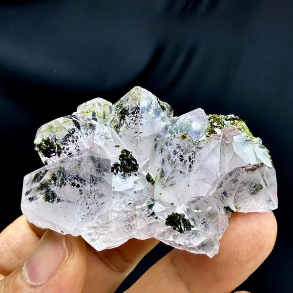 Clear garden quartz cluster with dark green epidote from Sichuan, China, held in hand