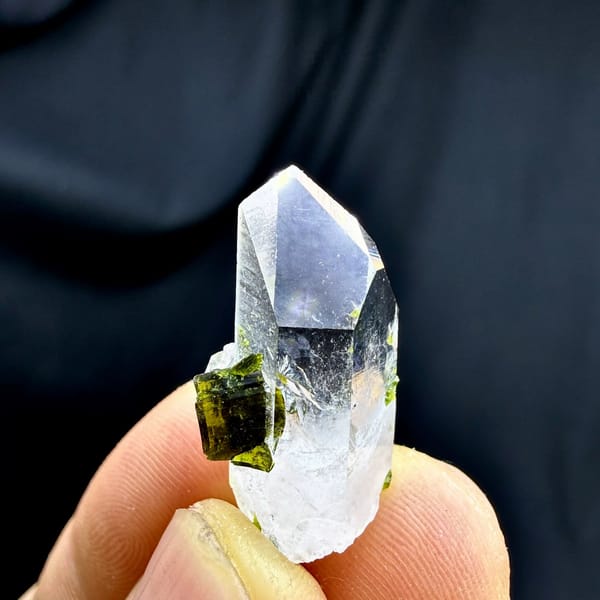 Small clear quartz point with green epidote from Sichuan, China, held in hand