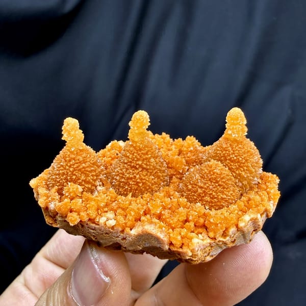 Orange gourd-shaped stalactitic calcite from Yunnan, China, held in hand