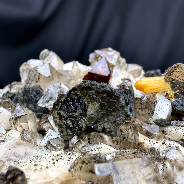 Red-brown helvine crystals on smoky quartz and feldspar from Yunxiao, Fujian, China, close-up of the crystal faces