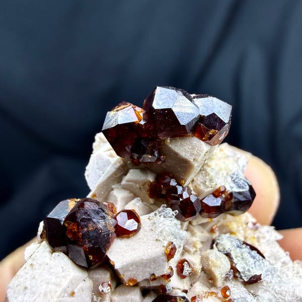 Glossy wine-red garnet crystals with hyalite opal on feldspar from Yunxiao, Fujian, China, close-up of the crystal faces