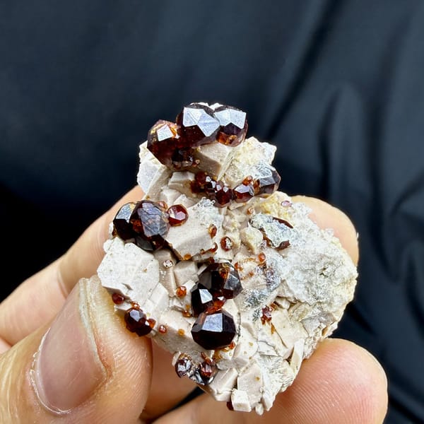 Glossy wine-red garnet crystals with hyalite opal on feldspar from Yunxiao, Fujian, China, detail of the matrix contact
