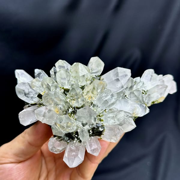 Flower-shaped fan of clear garden quartz with epidote from Sichuan, China, held in hand