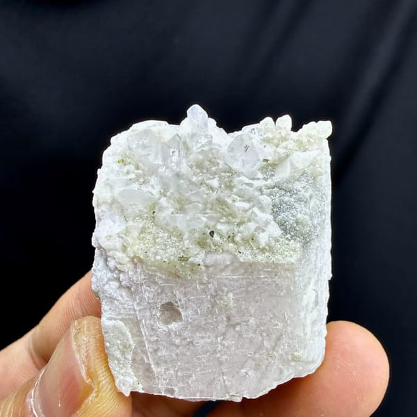 Pale pink feldspar crystal capped with quartz druse and mica from Pakistan, held in hand