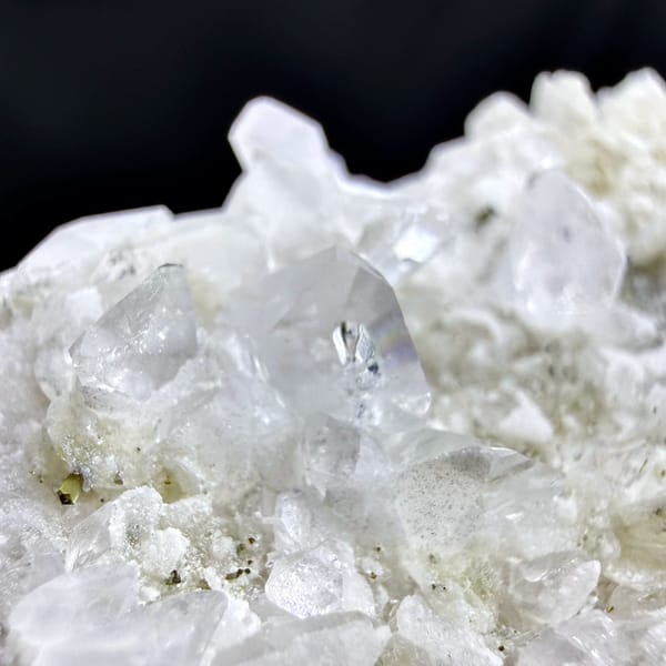 Pale pink feldspar crystal capped with quartz druse and mica from Pakistan, close-up of the crystal faces