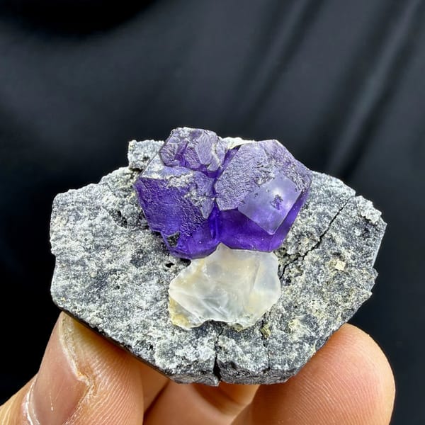 Etched violet-blue fluorite cubes with pale calcite on grey rock from Fujian, China