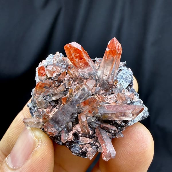 Red-skinned quartz needles on black specular hematite from Guangdong, China, close-up of the crystal faces