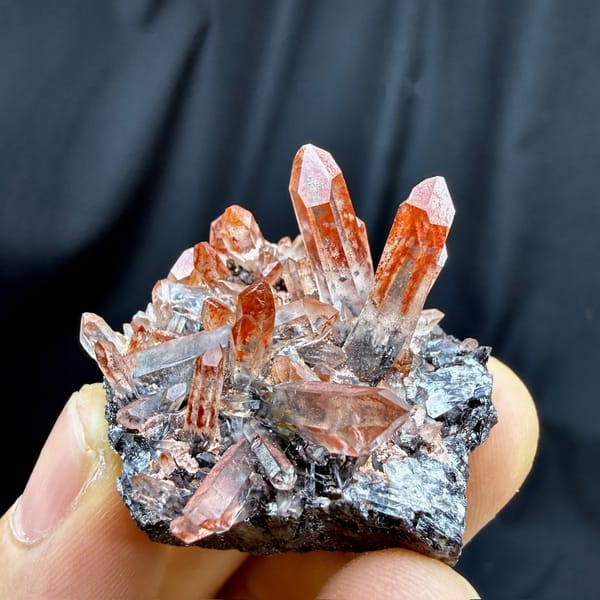 Red-skinned quartz needles on black specular hematite from Guangdong, China, detail of the matrix contact