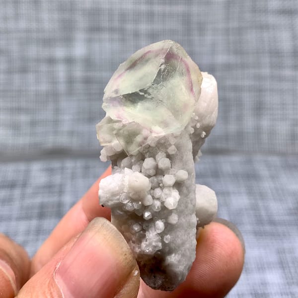 Purple-green fluorite cube on a pale quartz stalk from Inner Mongolia, China, close-up of the crystal faces