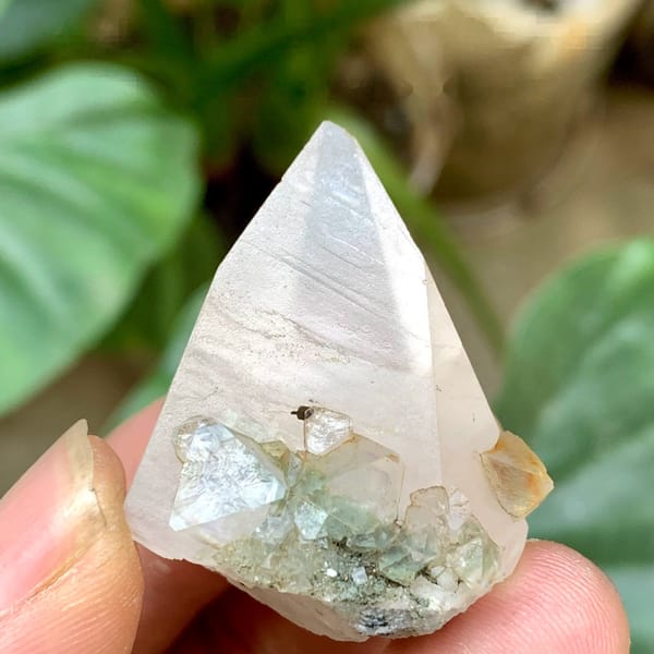 Milky calcite point with pale green fluorite octahedra from Fujian, China, held in hand