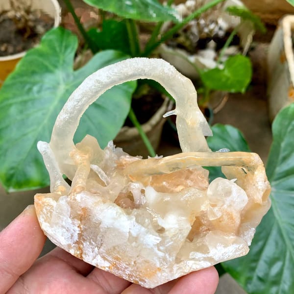 Arched calcite stalactite over crystal cluster from Yunnan, China, held in hand