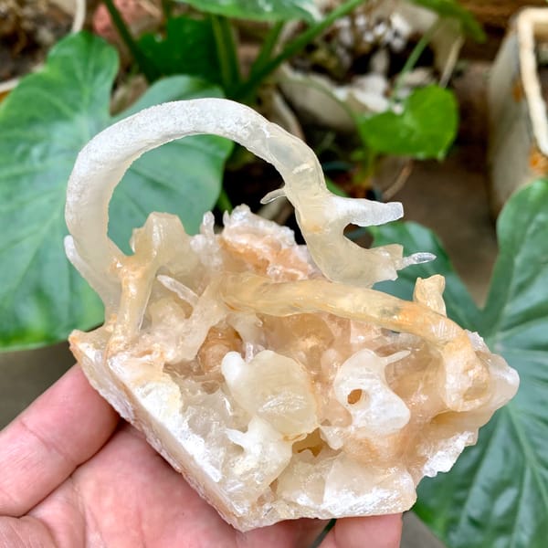 Arched calcite stalactite over crystal cluster from Yunnan, China, close-up of the crystal faces