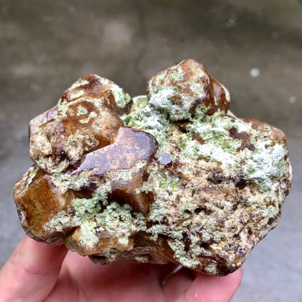 Large brown-green demantoid garnet crystal floater from Mali, held in hand