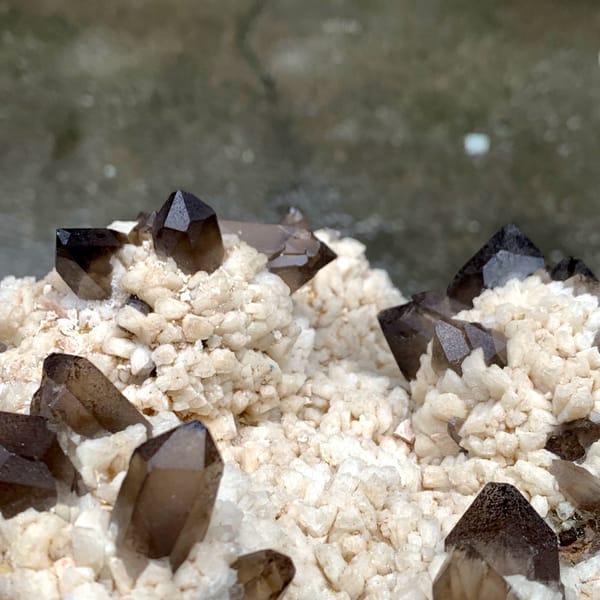 Dark smoky quartz points on cream feldspar mound from Fujian, China, close-up of the crystal faces