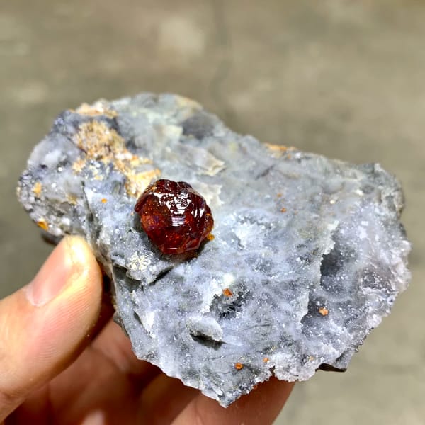 Gem-grade sphalerite crystal glowing orange-red when, from Hunan, China, front view in daylight, held in hand