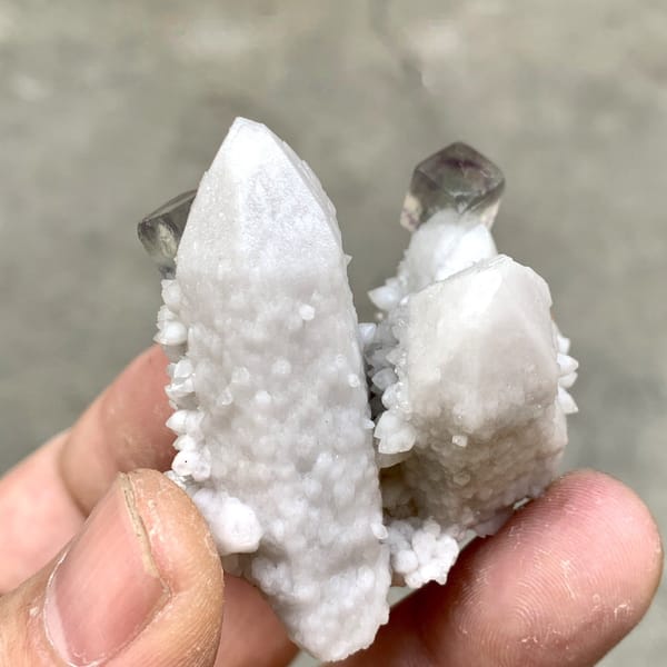 Pale quartz spire with small purple fluorite cubes from Inner Mongolia, China, detail of the matrix contact