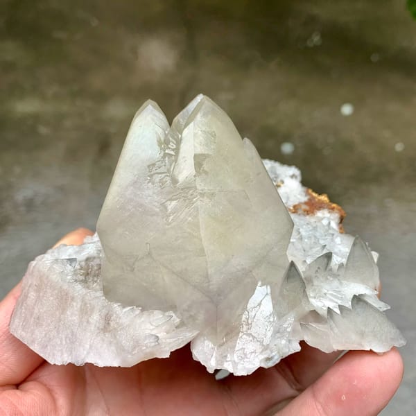 Large twinned calcite crystal with sketch-pattern lines from Hubei, China, held in hand