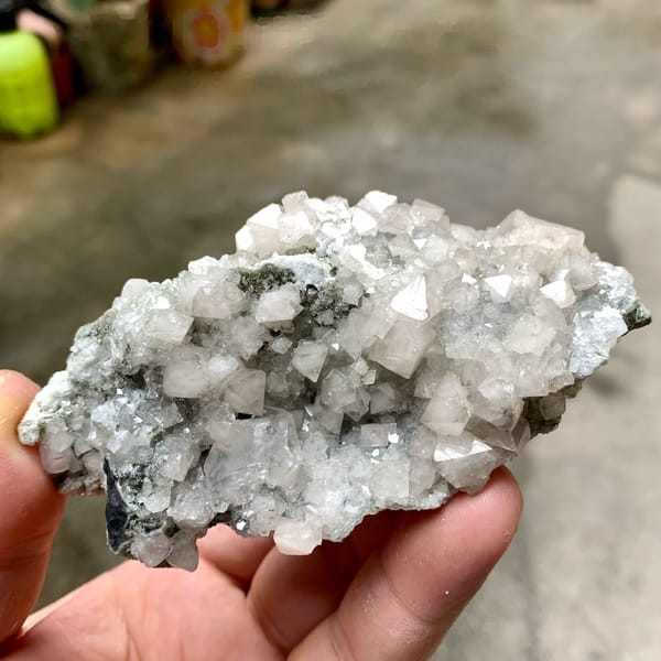 Pale scheelite crystals with white calcite from Yaogangxian Mine, Hunan, China, held in hand