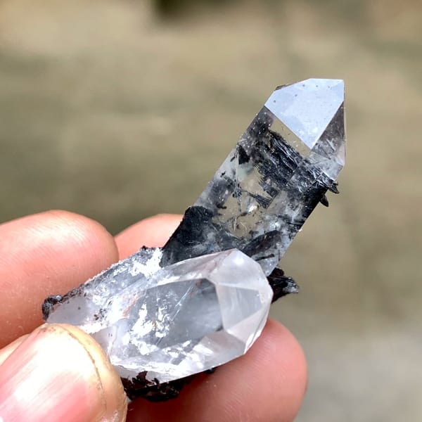 Two clear quartz prisms on black specular hematite from Guangdong, China, second angle