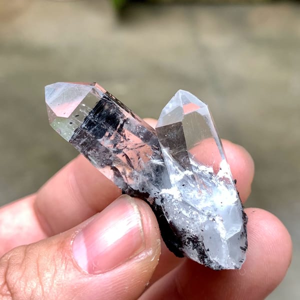 Two clear quartz prisms on black specular hematite from Guangdong, China, reverse side