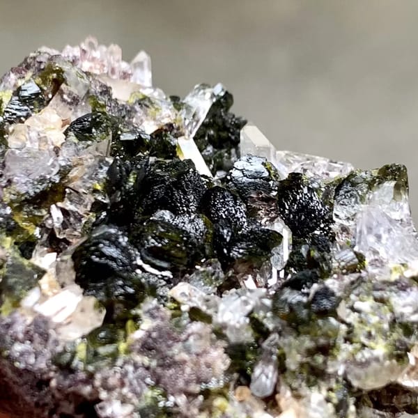 Dark green epidote blades with lilac quartz from Yunnan, China, close-up of the crystal faces