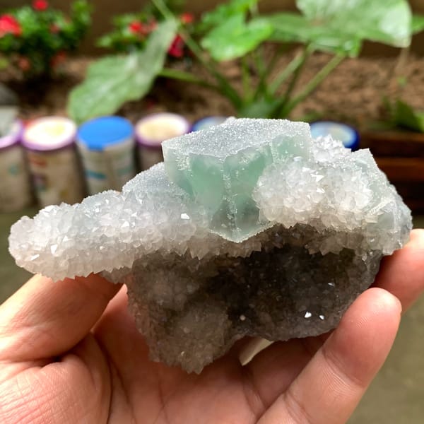 Bright green fluorite cube on sparkling quartz druse from Fujian, China, close-up of the crystal faces