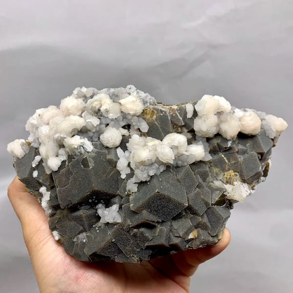 Dark garnet crystals with white calcite balls from Inner Mongolia, China, held in hand