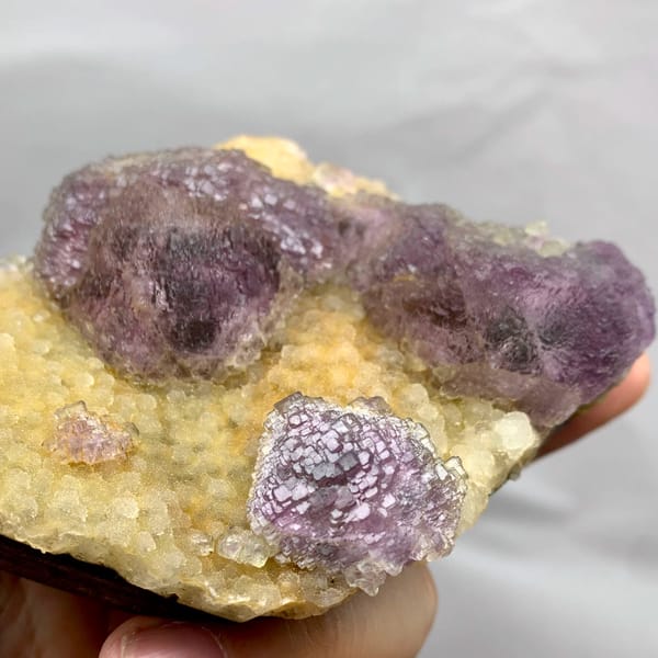 Purple mosaic fluorite balls on golden quartz druse from Fujian, China, close-up of the crystal faces