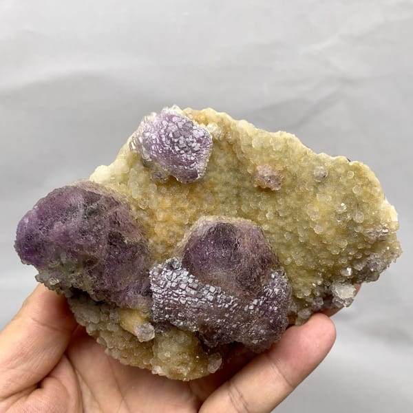 Purple mosaic fluorite balls on golden quartz druse from Fujian, China, detail of the matrix contact