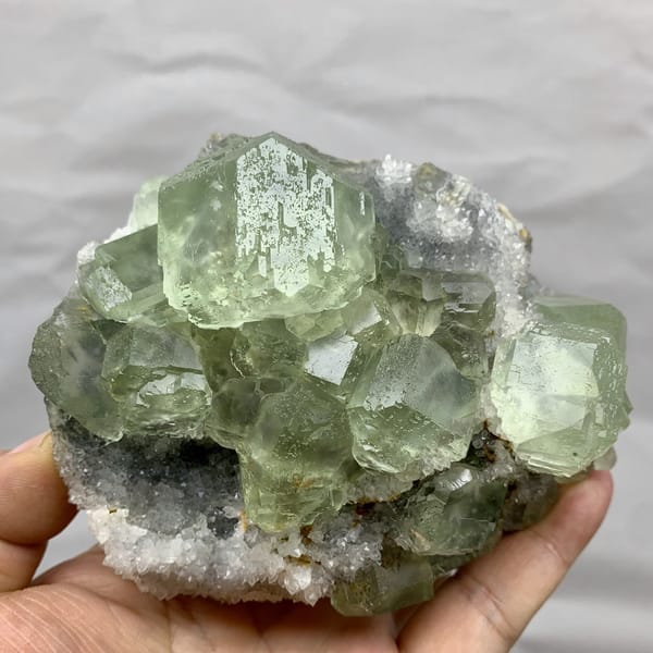 Cluster of large glassy sea-green fluorite cubes from Fujian, China, detail of the matrix contact