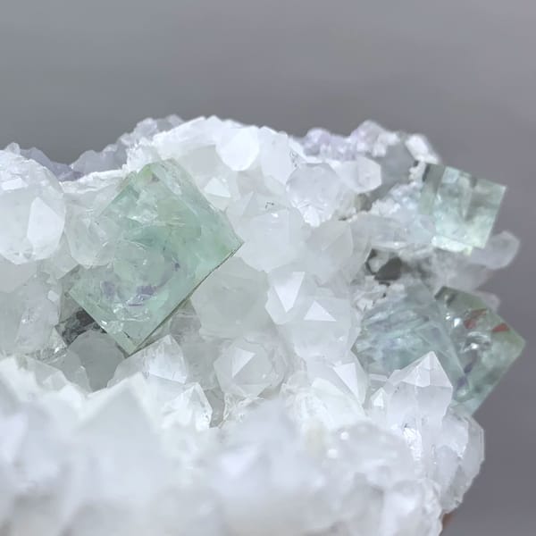 Glassy pale-green fluorite cubes in white quartz geode from Zhejiang, China, close-up of the crystal faces