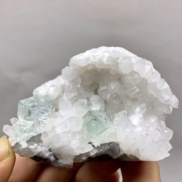 Glassy pale-green fluorite cubes in white quartz geode from Zhejiang, China, detail of the matrix contact