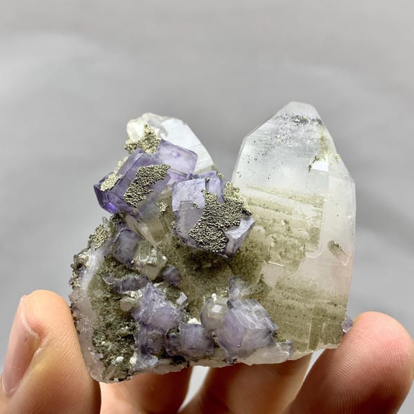 Purple fluorite cubes with pyrite on clear quartz from Yaogangxian Mine, Hunan, China, detail of the matrix contact