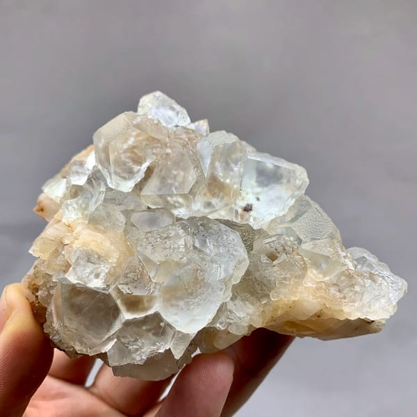 Etched white fluorite octahedra with calcite from Inner Mongolia, China, held in hand