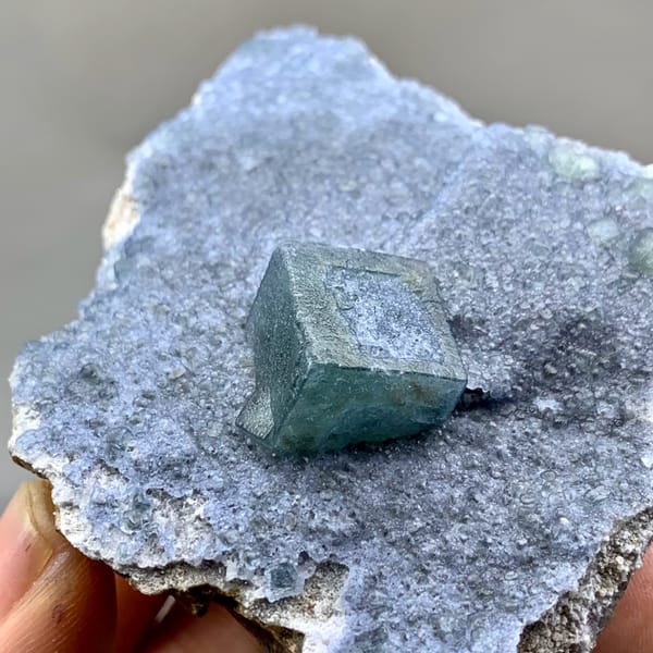Teal fluorite cube on dusty lavender recrystallised fluorite from Inner Mongolia, China, close-up of the crystal faces