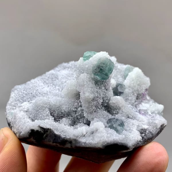 Blue-green fluorite cubes on frosted lavender and white mound from Fujian, China, close-up of the crystal faces