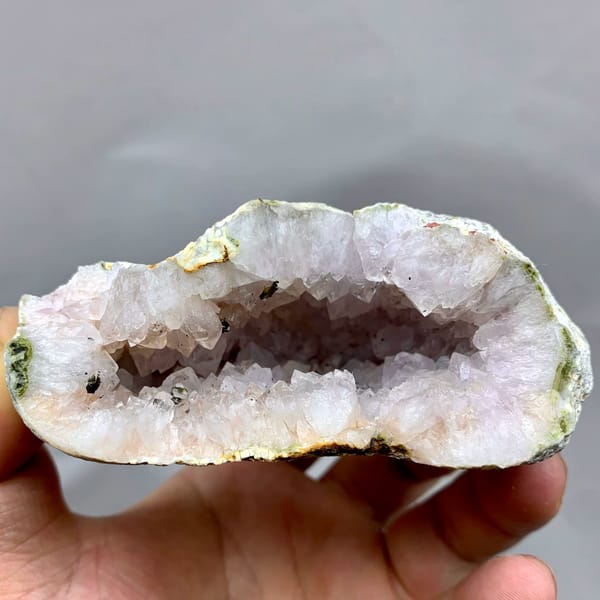 Pale lilac quartz geode with green epidote from Sichuan, China, held in hand