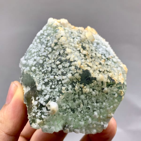 Green sugar-textured fluorite block with white calcite dots from Fujian, China, close-up of the crystal faces