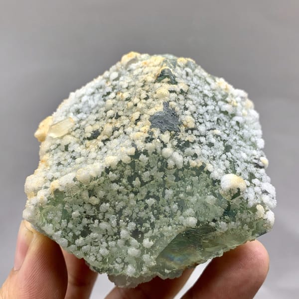Green sugar-textured fluorite block with white calcite dots from Fujian, China, detail of the matrix contact