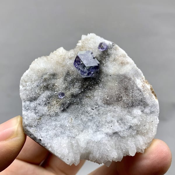 Single blue fluorite crystal on grey quartz druse from Fujian, China, detail of the matrix contact
