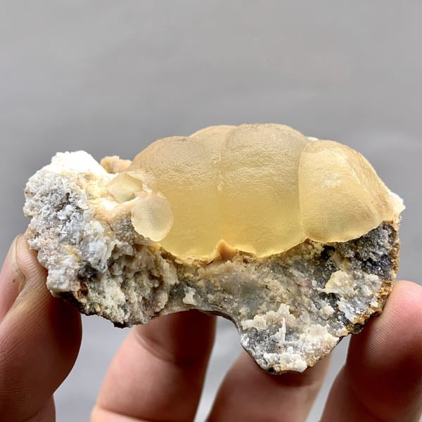 Large honey-yellow botryoidal fluorite ball on grey matrix from Henan, China, detail of the matrix contact