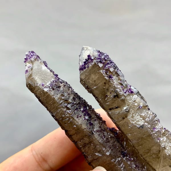 Two tea-brown quartz prisms with purple fluorite caps from Inner Mongolia, China, reverse side