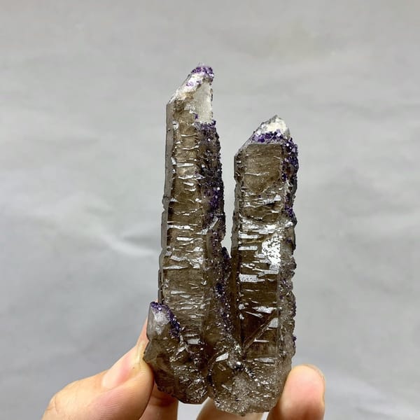 Two tea-brown quartz prisms with purple fluorite caps from Inner Mongolia, China, detail of the matrix contact